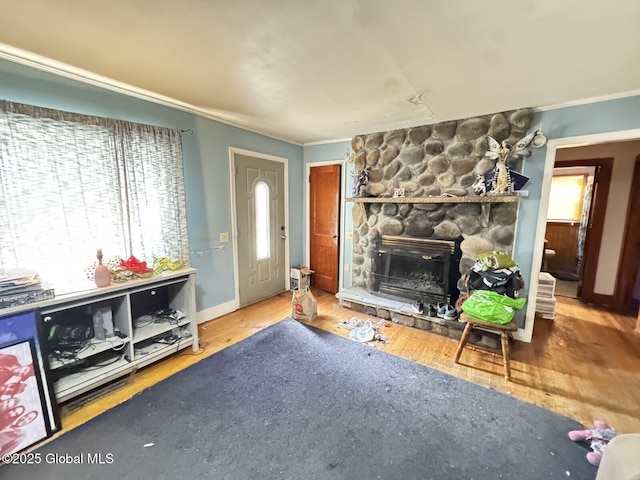 living room featuring a stone fireplace, ornamental molding, and wood finished floors