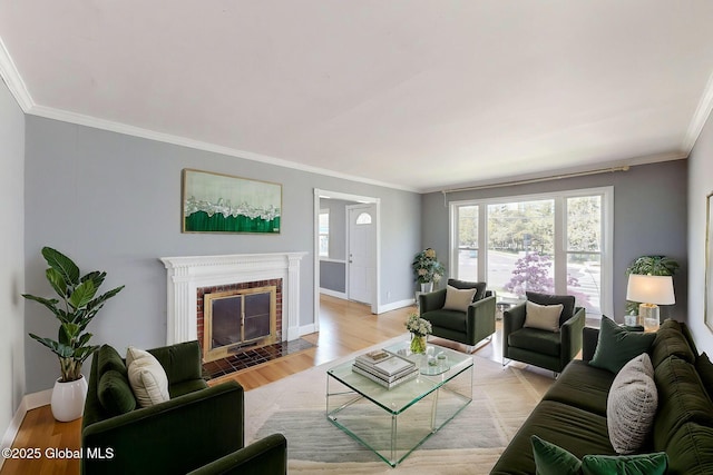 living room featuring baseboards, ornamental molding, a brick fireplace, and light wood finished floors