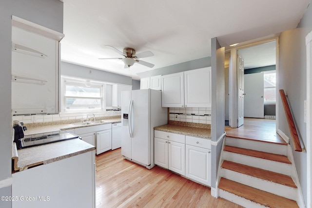 kitchen featuring a ceiling fan, a healthy amount of sunlight, a sink, backsplash, and white fridge with ice dispenser