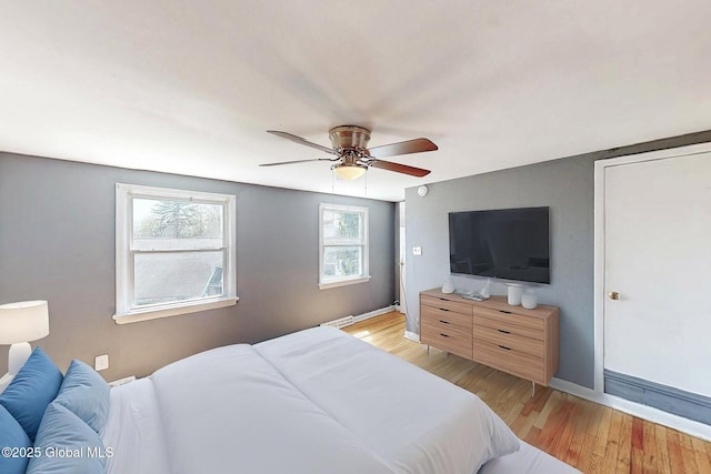 bedroom with light wood-style floors, baseboards, and a ceiling fan