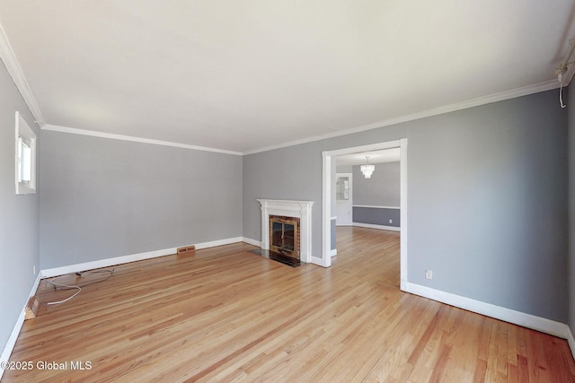 unfurnished living room featuring visible vents, a fireplace with flush hearth, wood finished floors, baseboards, and ornamental molding