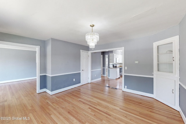 interior space featuring baseboards, light wood-style flooring, and a notable chandelier