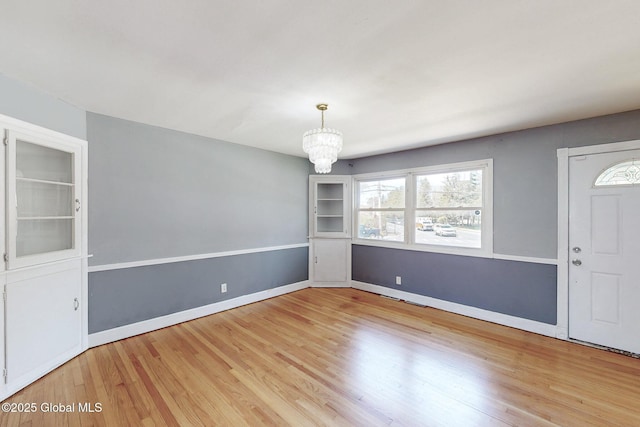 interior space featuring baseboards, wood finished floors, and a notable chandelier
