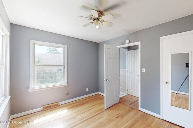 unfurnished bedroom featuring baseboards, ceiling fan, wood finished floors, and visible vents