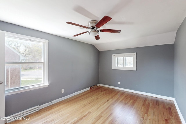 spare room with baseboards, ceiling fan, wood finished floors, and lofted ceiling