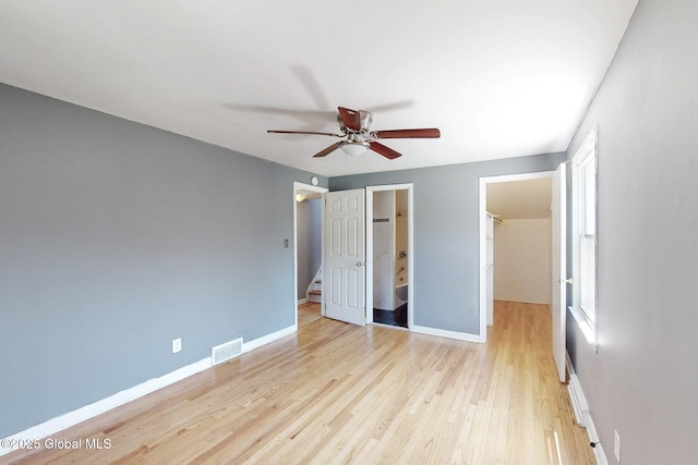 unfurnished bedroom featuring light wood-style flooring, baseboards, a spacious closet, visible vents, and a closet
