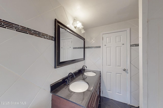 bathroom featuring double vanity, tile walls, a sink, and tile patterned flooring