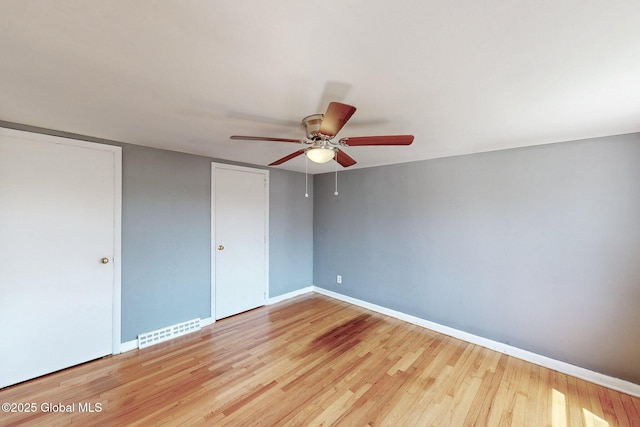 unfurnished bedroom featuring visible vents, a ceiling fan, baseboards, and wood finished floors