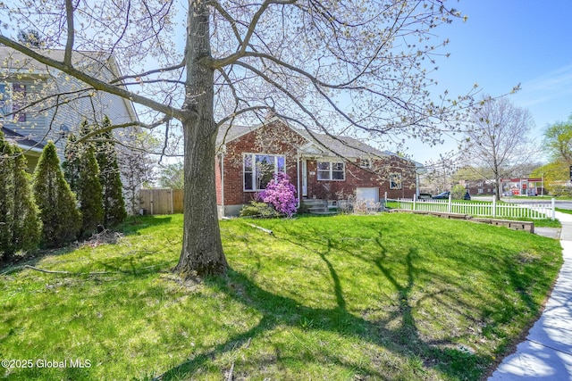 view of front of home with brick siding, fence, and a front yard