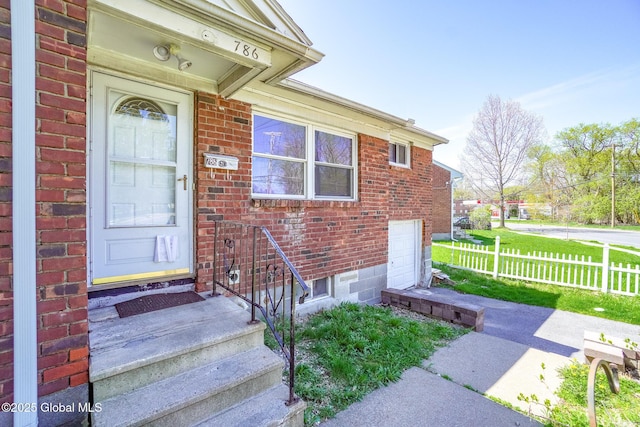 property entrance with fence and brick siding