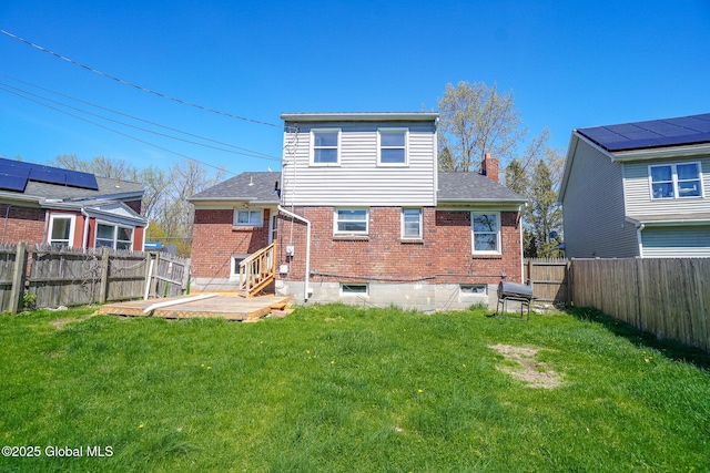 rear view of house with brick siding, a fenced backyard, a yard, and a chimney