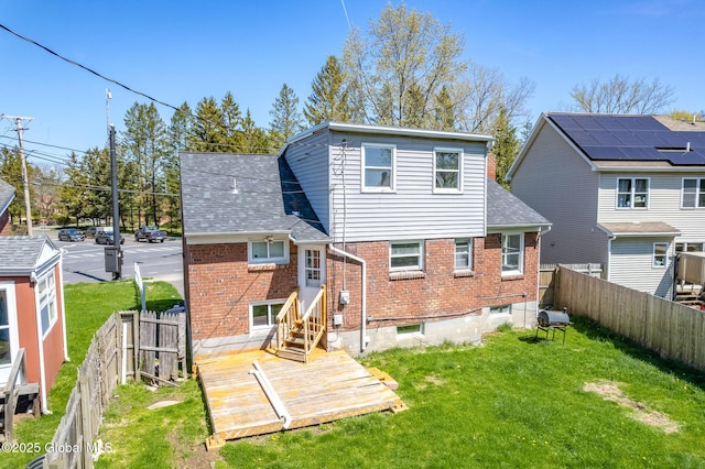 back of property with entry steps, a yard, a fenced backyard, and brick siding