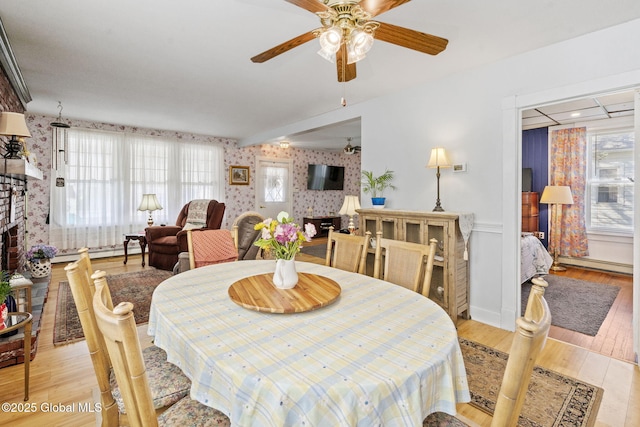 dining room with a ceiling fan, wallpapered walls, and baseboard heating