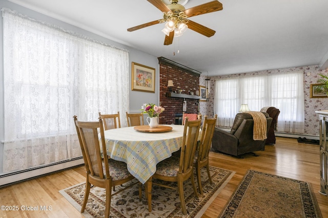 dining area with light wood-style flooring, ceiling fan, baseboard heating, and wallpapered walls