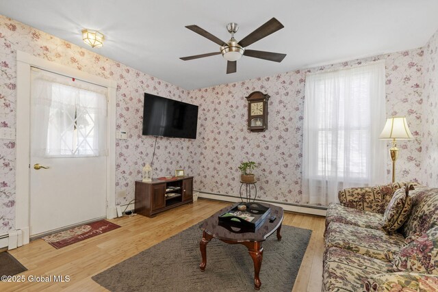 living room with ceiling fan, plenty of natural light, wood finished floors, and a baseboard radiator