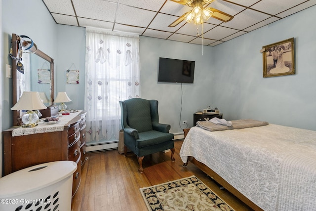 bedroom with a baseboard radiator, a drop ceiling, and dark wood-style floors