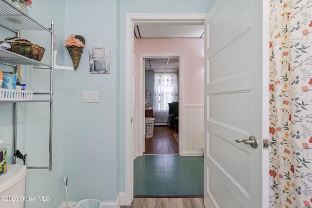 hallway with a wainscoted wall, attic access, and wood finished floors