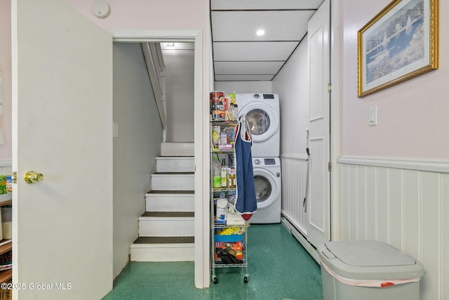 laundry room with stacked washer and dryer, laundry area, and a wainscoted wall