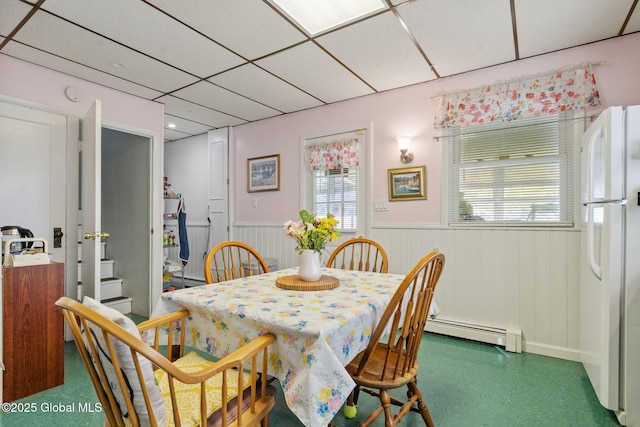 dining area featuring a paneled ceiling, tile patterned floors, a wainscoted wall, and a baseboard radiator