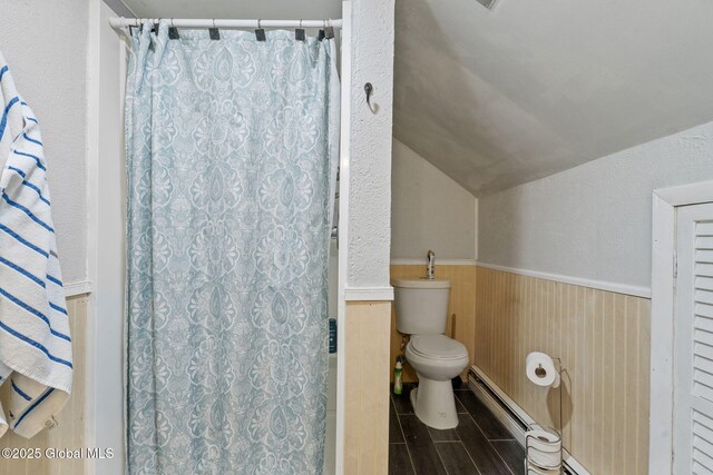 full bath featuring wainscoting, lofted ceiling, toilet, a baseboard heating unit, and a shower with curtain