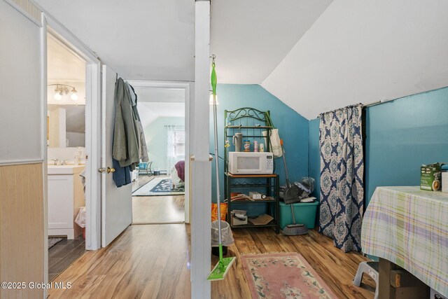 bedroom featuring ensuite bath, wood finished floors, and lofted ceiling