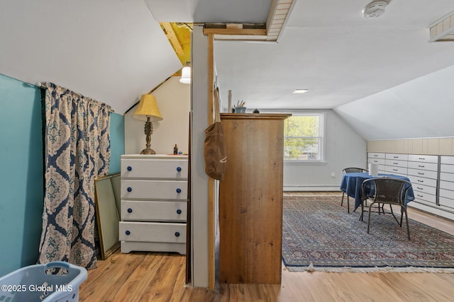 interior space featuring a baseboard radiator, vaulted ceiling, and wood finished floors