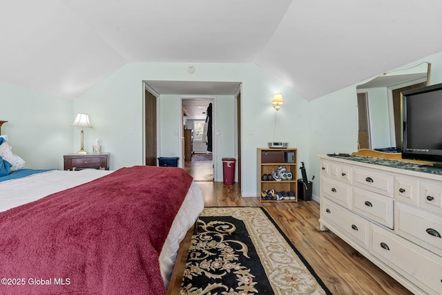 bedroom with light wood-style floors and lofted ceiling