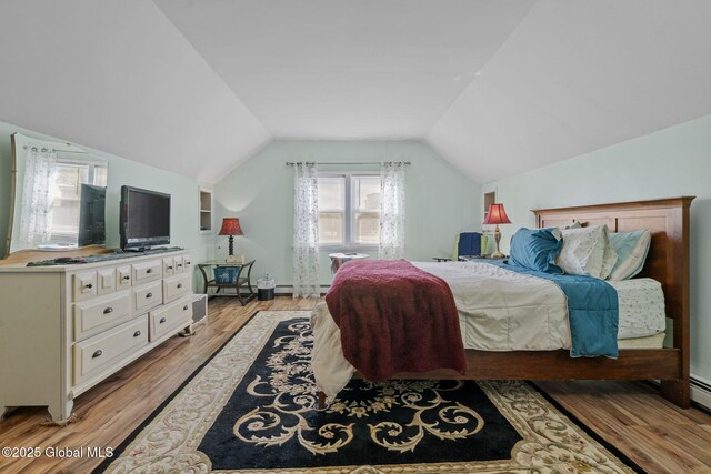 bedroom with light wood-style floors, baseboards, a baseboard heating unit, and lofted ceiling