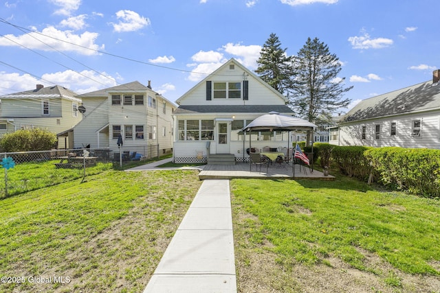 rear view of house with a lawn, a patio, a gazebo, and a fenced backyard