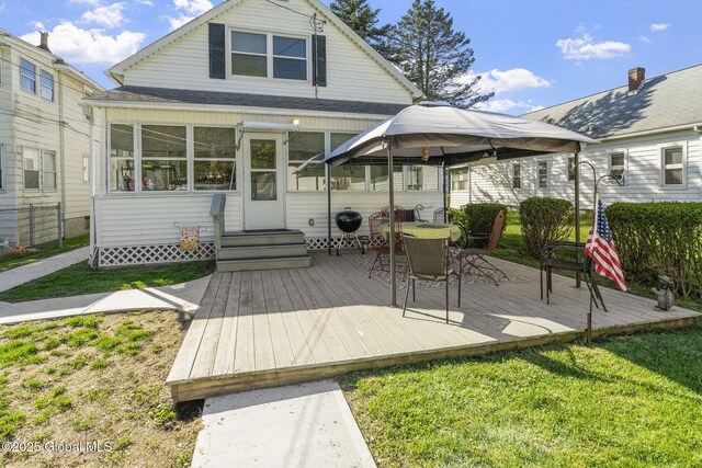 rear view of house featuring a lawn, a wooden deck, and a shingled roof
