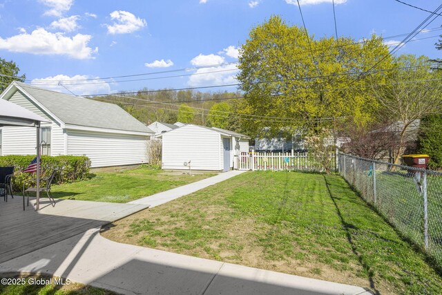 view of yard featuring a fenced backyard, a wooden deck, and an outbuilding
