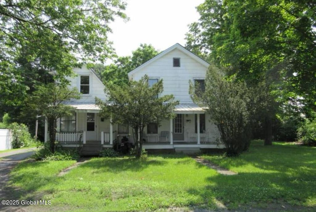 view of front of house with covered porch, metal roof, and a front lawn