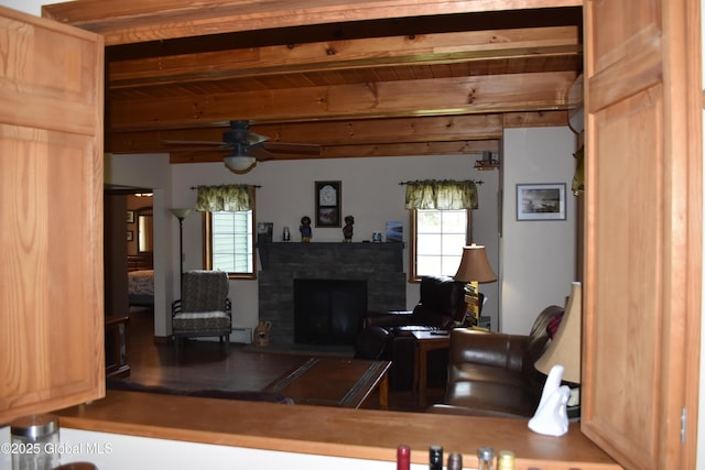 living area featuring a fireplace, ceiling fan, and beamed ceiling