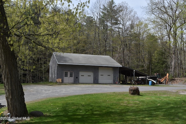 garage with a garage, dirt driveway, and a forest view