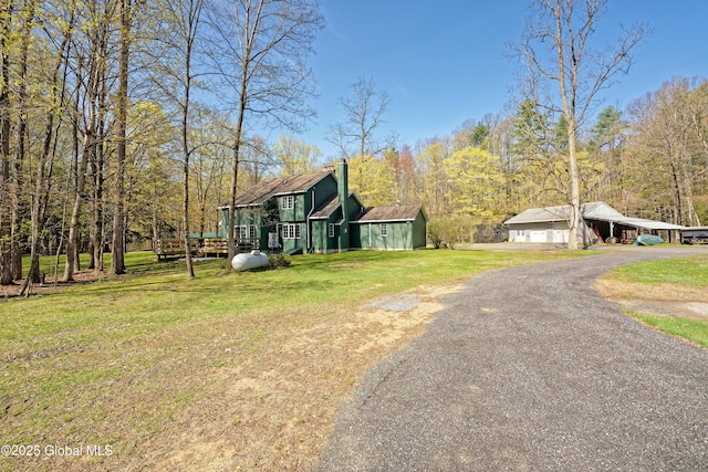 exterior space featuring a chimney, a yard, and driveway