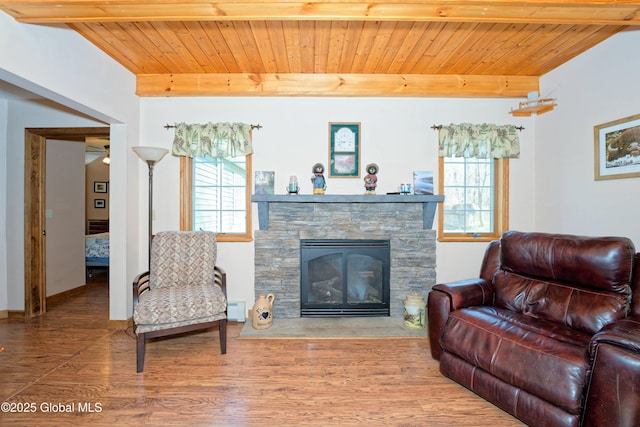 living area featuring beam ceiling, a fireplace, wood finished floors, and wooden ceiling