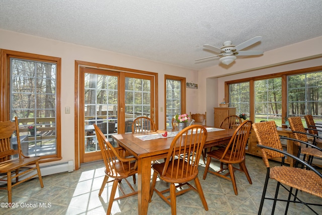 dining room featuring a ceiling fan, a textured ceiling, a baseboard heating unit, and a wealth of natural light