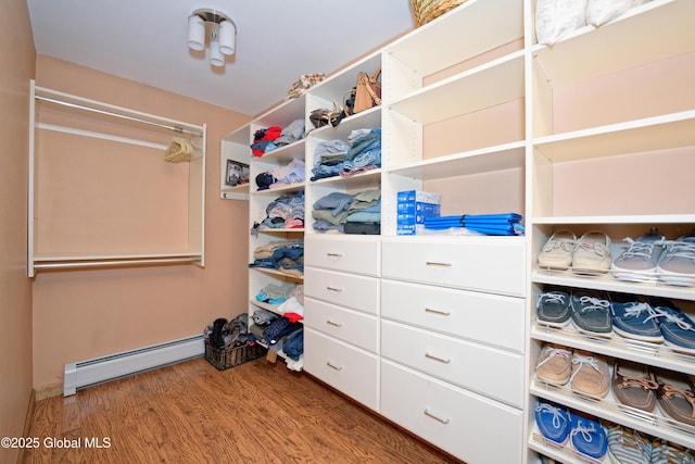 spacious closet with wood finished floors and a baseboard heating unit