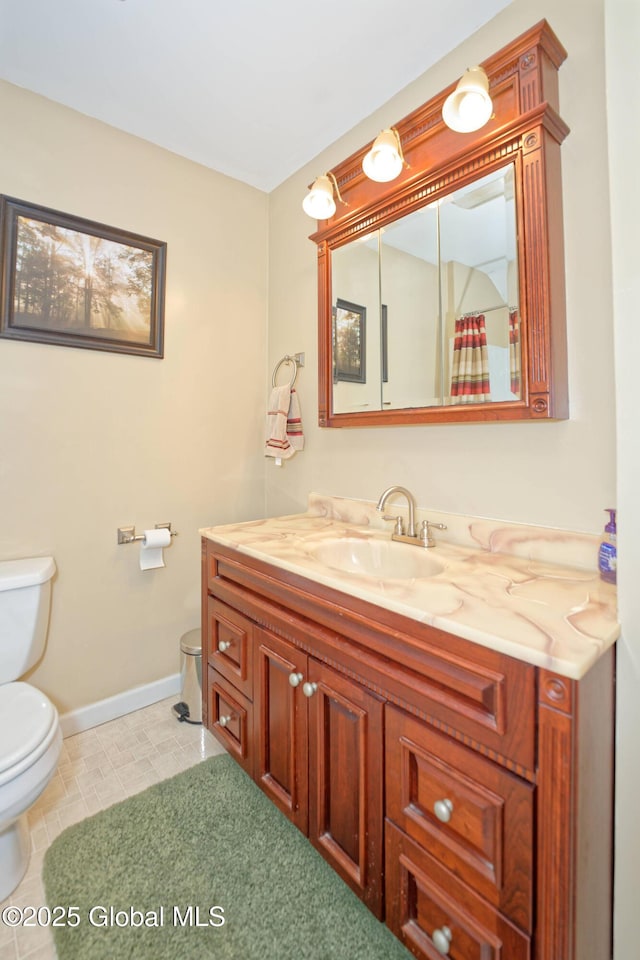 bathroom with baseboards, vanity, and toilet
