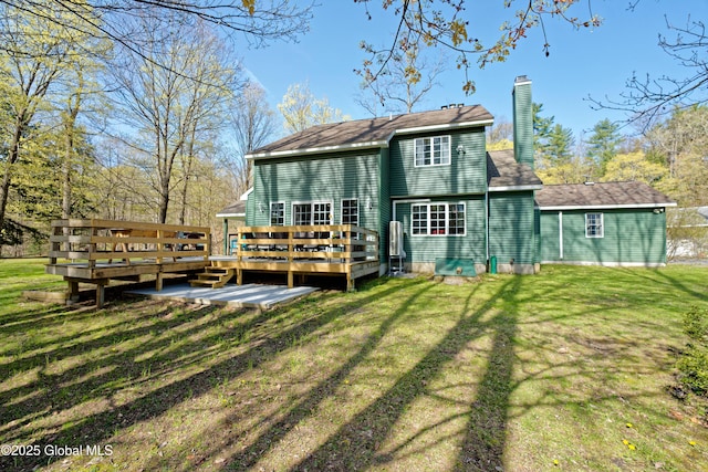 back of house with a yard, a wooden deck, and a chimney