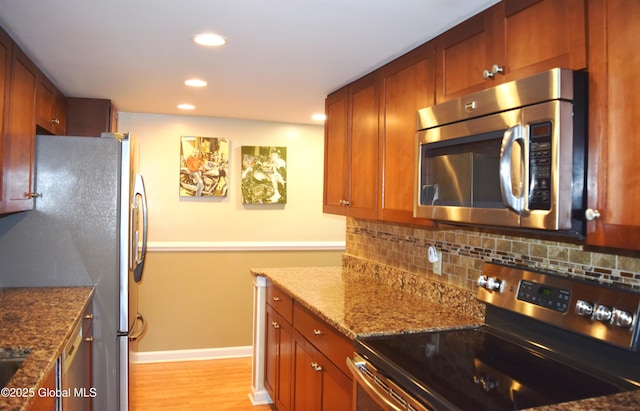kitchen with decorative backsplash, appliances with stainless steel finishes, light wood-type flooring, stone counters, and recessed lighting