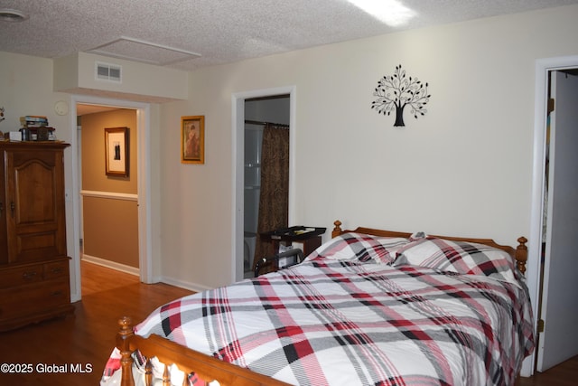 bedroom with visible vents, baseboards, a textured ceiling, and wood finished floors