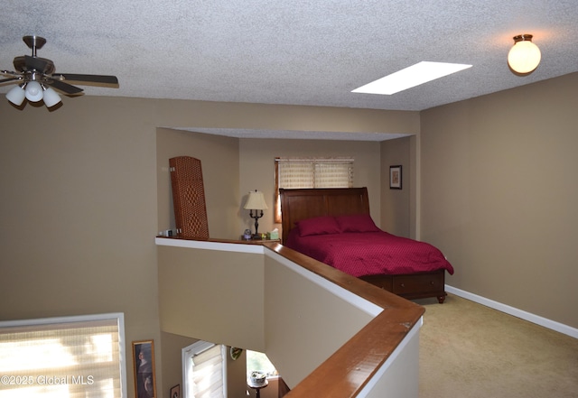 carpeted bedroom featuring baseboards, a textured ceiling, and a skylight