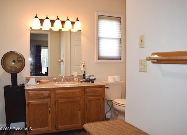 bathroom featuring a healthy amount of sunlight, vanity, and toilet