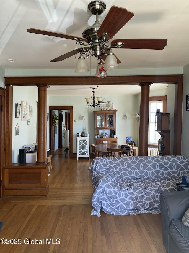 bedroom with wood-type flooring, decorative columns, and radiator heating unit