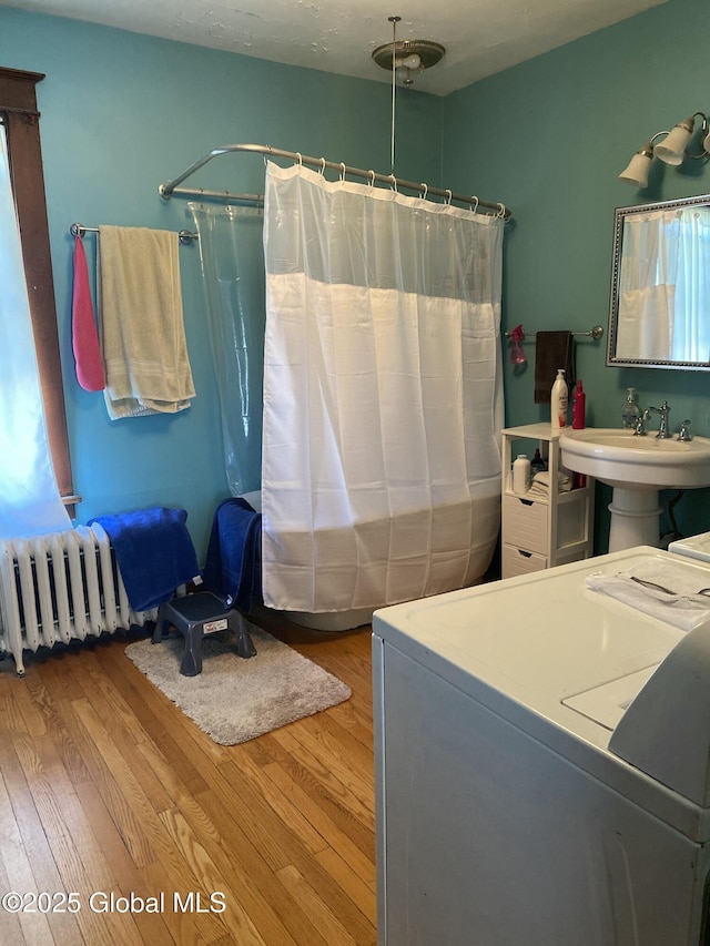 interior space featuring laundry area, radiator, washer / clothes dryer, and wood finished floors