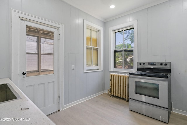 502 1st St, Albany, NY 12206 - kitchen with stainless steel electric stove, radiator, ornamental molding, light wood-style floors, and baseboards