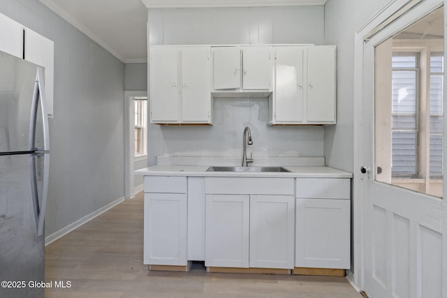 502 1st St, Albany, NY 12206 - kitchen with freestanding refrigerator, a sink, white cabinets, light wood-type flooring, and light countertops