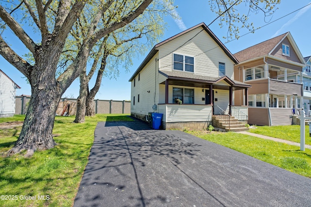 view of front of property with fence, a front yard, and aphalt driveway