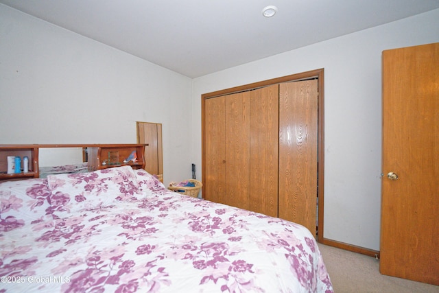 bedroom with a closet, carpet flooring, baseboards, and vaulted ceiling